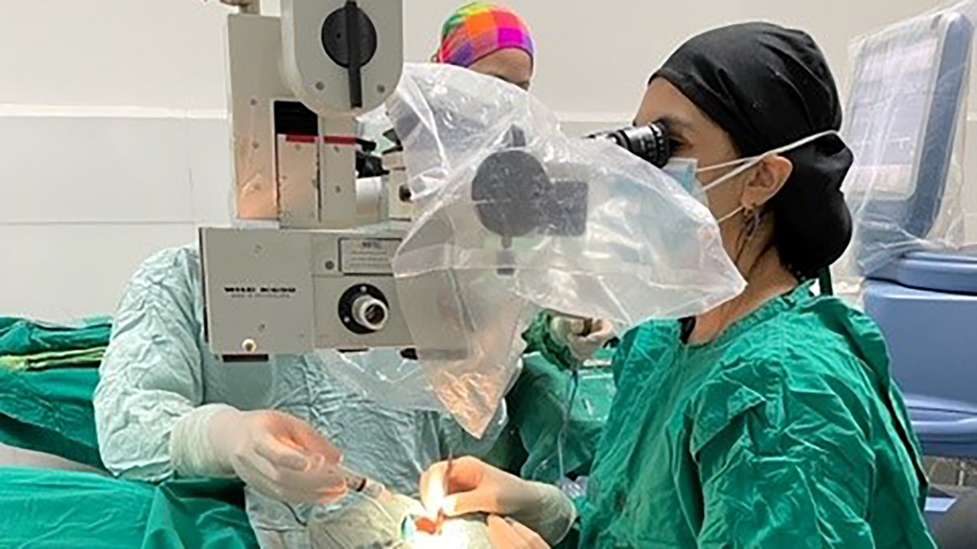 fully masked and suited-up surgeon conducting eye surgery