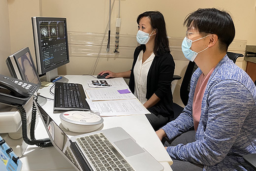 two people wearing masks over their noses and mouths look at images on a computer